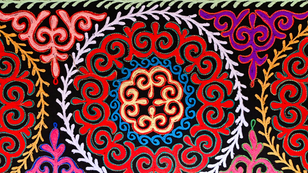 Close-up traditional Mongolian embroidery pattern with multiple rings of white, red, blue and yellow (1920 x 1080)