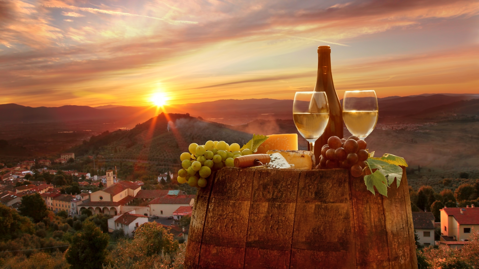 The image depicts a picturesque sunset over a vineyard in Tuscany, Italy, featuring a wooden barrel with a bottle of white wine, two glasses of wine, grapes, and cheese, creating a serene and inviting atmosphere.